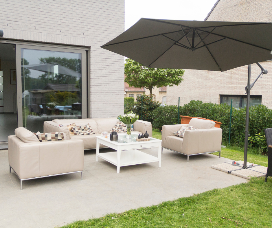 a modern outdoor patio with a large umbrella, table, and several chairs.