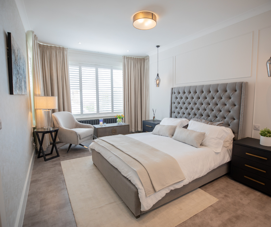 a bedroom with a large bed, two windows, a chair, and a nightstand.